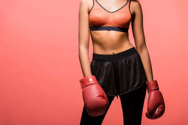 Cropped view of african american sportswoman in boxing gloves posing isolated on coral with copy space — Stock Photo