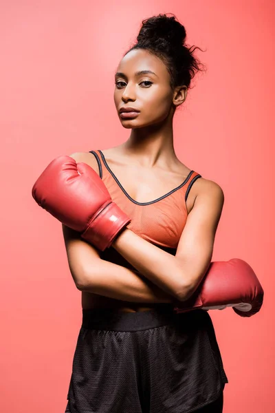 Hermosa deportista afroamericana en guantes de boxeo mirando a la cámara aislada en coral - foto de stock