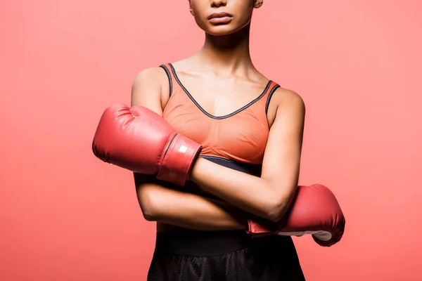 Vista recortada de la deportista afroamericana en guantes de boxeo posando aislada en coral - foto de stock