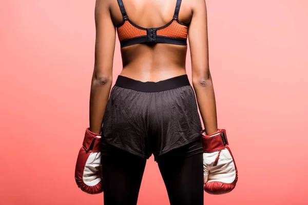 Back view of african american sportswoman in boxing gloves isolated on coral — Stock Photo