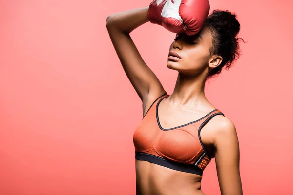 Beautiful african american sportswoman in boxing glove posing isolated on coral with copy space — Stock Photo