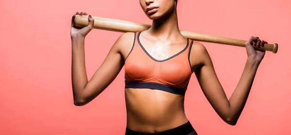 Plano panorámico de la deportista afroamericana posando con bate de béisbol aislado en coral - foto de stock