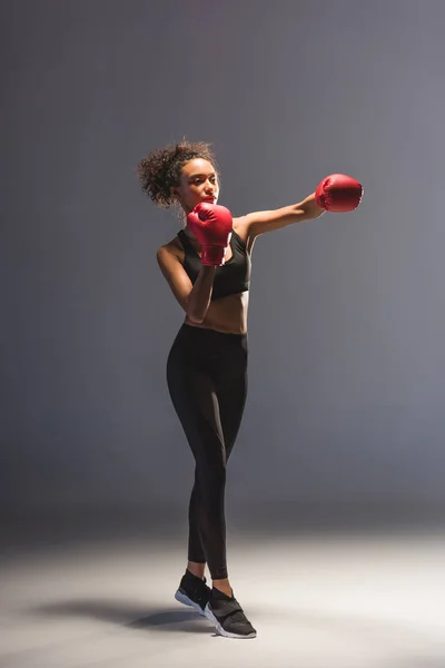 Beautiful athletic african american sportswoman boxing on black — Stock Photo
