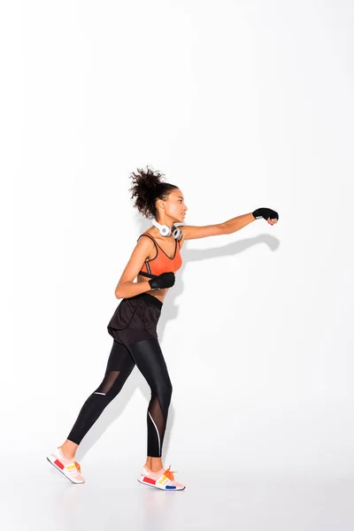 Sportive afro-américaine sportive avec casque d'entraînement en gants de sport sur blanc — Photo de stock