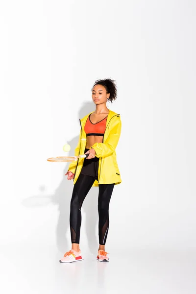 Atletica sportiva afroamericana che si esercita con racchetta da tennis e palla su bianco — Foto stock