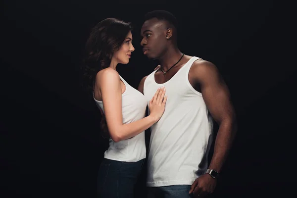 Beautiful sensual interracial couple in white tank tops isolated on black — Stock Photo