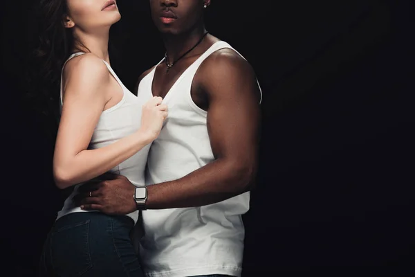 Recortado vista de seductora pareja interracial abrazando aislado en negro con espacio de copia - foto de stock