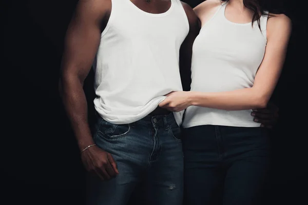 Partial view of woman undressing muscular african american man isolated on black — Stock Photo