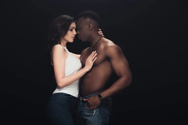 Beautiful seductive woman embracing shirtless african american man isolated on black with copy space — Stock Photo