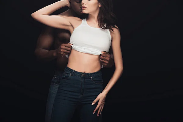 Cropped view of african american man undressing seductive woman isolated on black with copy space — Stock Photo