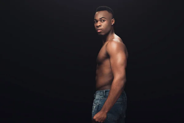 Schöner hemdloser afrikanisch-amerikanischer Mann in Jeans, der isoliert auf schwarz mit Kopierraum in die Kamera schaut — Stockfoto