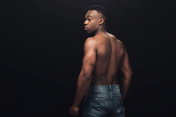 Espalda vista de sexy muscular africano americano hombre en denim posando aislado en negro con espacio de copia - foto de stock