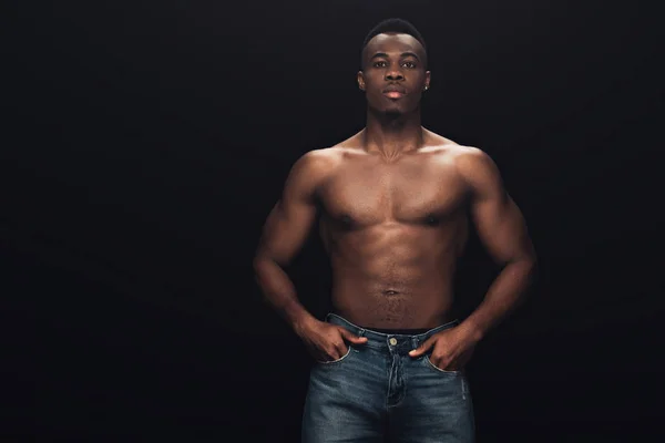 Handsome shirtless african american man with hands in pockets posing isolated on black — Stock Photo