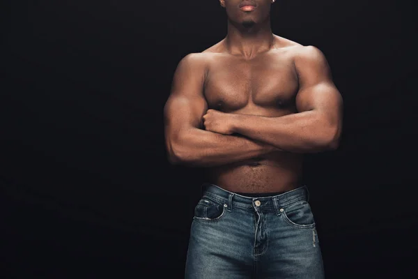 Corte vista de sexy muscular afro-americano homem em jeans posando com cruzados braços isolados no preto — Fotografia de Stock