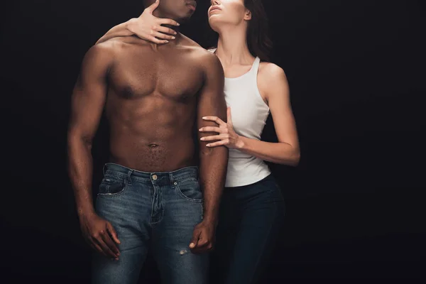 Cropped view of woman embracing shirtless african american man isolated on black — Stock Photo