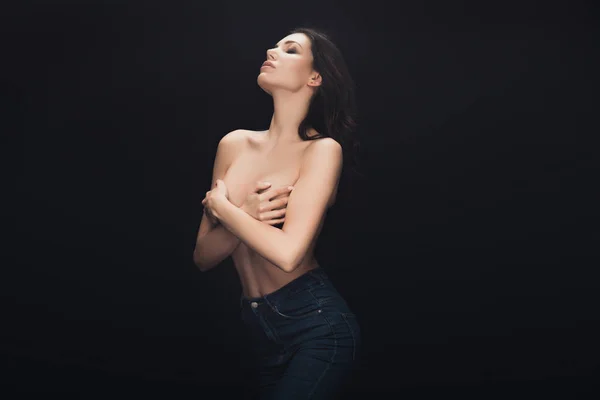 Hermosa chica sexy cubriendo los pechos con las manos y posando aislado en negro - foto de stock