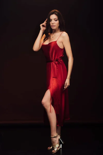 Bella donna sensuale in abito rosso in posa con gli occhi chiusi isolati su nero — Foto stock