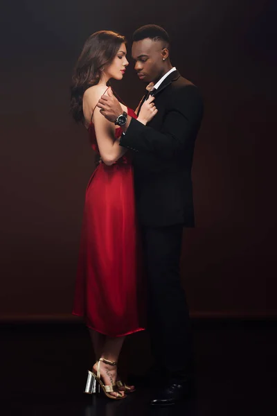 Beautiful interracial couple in formal wear posing isolated on black — Stock Photo