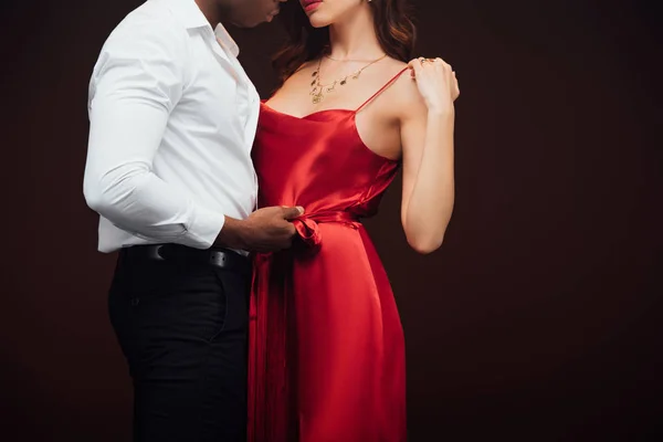 Cropped view of african american man embracing woman in red dress isolated on black with copy space — Stock Photo