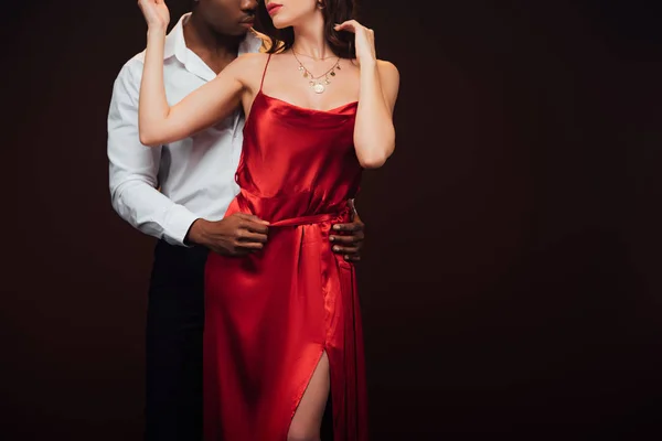 Partial view of african american man embracing woman in red dress isolated on black with copy space — Stock Photo