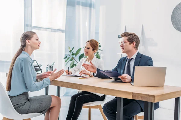 Atractiva mujer hablando con los reclutadores durante la entrevista de trabajo - foto de stock