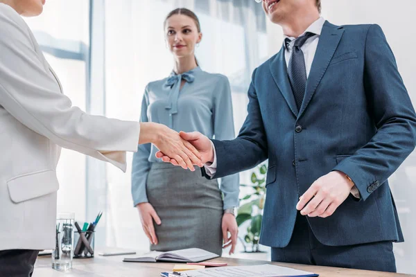 Ausgeschnittener Blick auf fröhlichen Personalvermittler, der Frau nahe attraktiver Bürokollegin die Hand schüttelt — Stockfoto