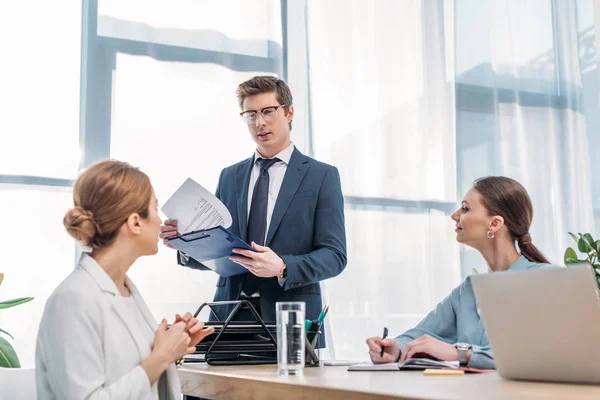 Handsome recruiter holding clipboard and looking at woman in job interview — Stock Photo