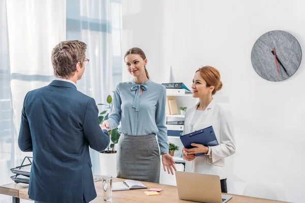 Rückansicht von Mann beim Händeschütteln mit glücklichem Personalvermittler in der Nähe von Amtskollegen — Stockfoto