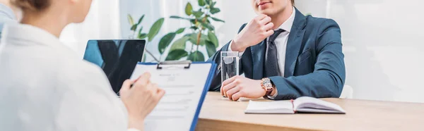 Prise de vue panoramique d'employé coûteux assis près du recruteur avec presse-papiers — Photo de stock