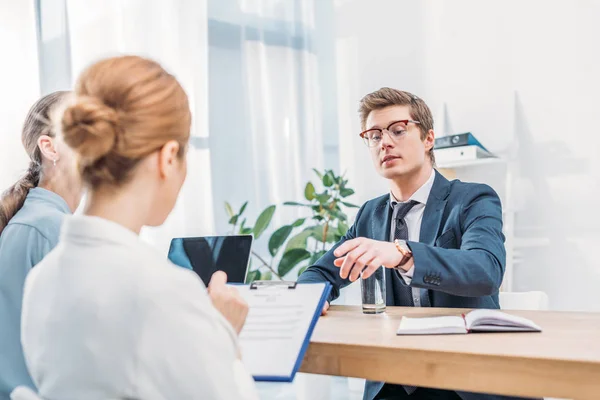 Enfoque selectivo del hombre en gafas apuntando con el dedo al reclutador con portapapeles - foto de stock