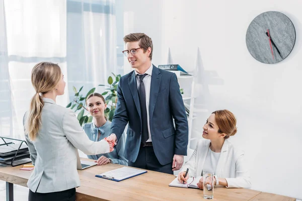 Hombre alegre en gafas estrechando la mano con reclutador en entrevista de trabajo - foto de stock