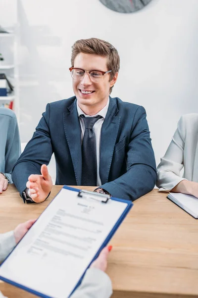 Foyer sélectif de recruteur joyeux près de collègues et de la femme tenant presse-papiers sur l'entrevue d'emploi — Photo de stock