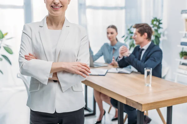 Cropped view of cheerful recruiter standing with crossed arms near coworkers — Stock Photo