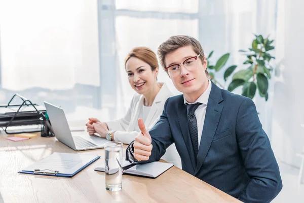 Handsome recruiter in glasses showing thumb up near cheerful coworker — Stock Photo