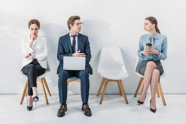 Handsome man in glasses sitting with laptop and talking with attractive woman — Stock Photo