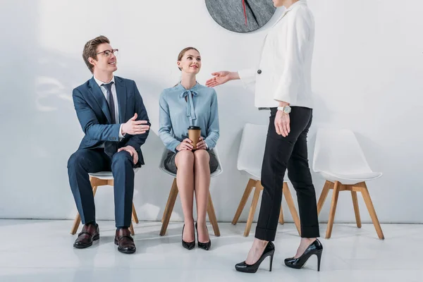 Vista recortada de reclutador de pie y gestos cerca de mujer atractiva y hombre alegre en gafas - foto de stock