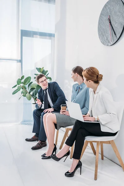 Felice uomo in occhiali parlando con donne attraenti in attesa di colloquio di lavoro — Foto stock