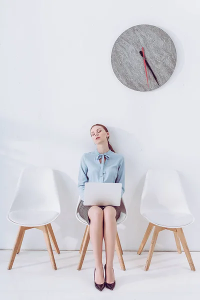Atractiva mujer con portátil durmiendo en la silla mientras espera entrevista de trabajo - foto de stock