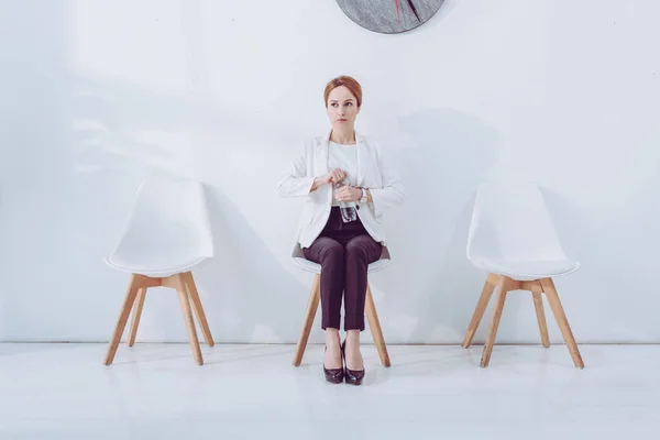 Attraktive Mitarbeiterin sitzt auf Stuhl und hält Flasche mit Wasser — Stockfoto