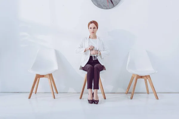 Attractive employee sitting on chair and holding bottle with water — Stock Photo