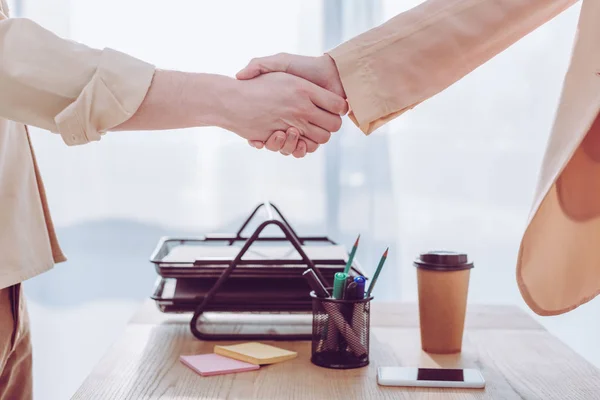 Cropped view of employee and recruiter shaking hands in office — Stock Photo