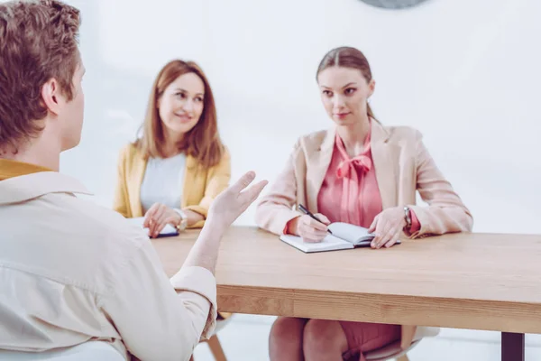 Selective focus of man talking and gesturing near attractive recruiters on job interview — Stock Photo