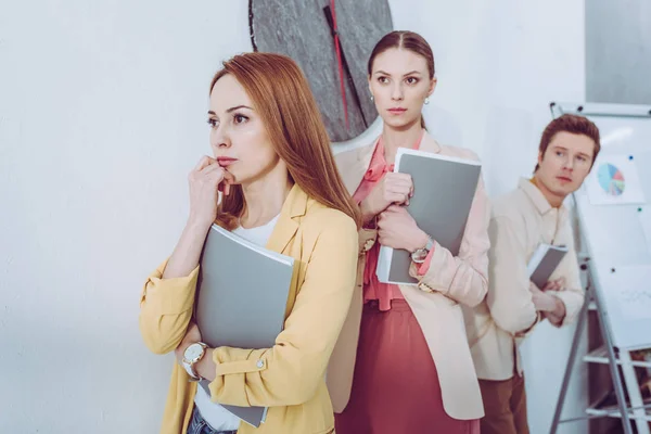 Selektiver Fokus besorgter attraktiver Frauen und Männer, die vor Ordnern anstehen — Stockfoto