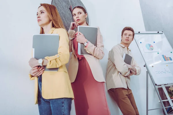 Low angle view of worried attractive women and man waiting in line with folders — Stock Photo