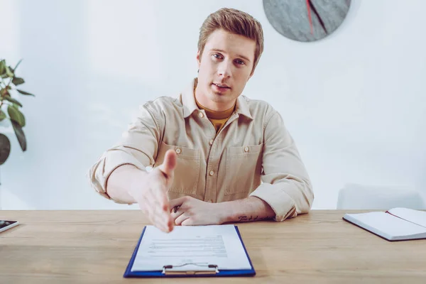Selective focus of handsome recruiter gesturing near clipboard — Stock Photo
