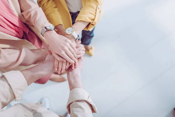 Cropped view of man and women putting hands together — Stock Photo