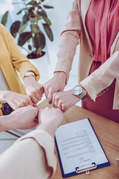 Cropped view of man and women giving fist bump in office — Stock Photo