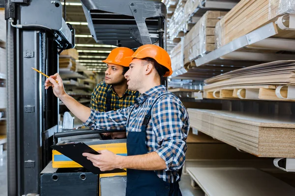 Multicultural workers in uniform and plaid shirts working in warehouse — Stock Photo