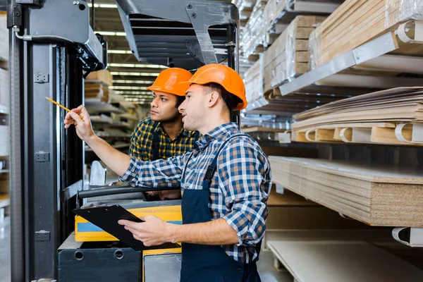 Multikulti-Arbeiter in Uniform und karierten Hemden arbeiten im Lager — Stockfoto