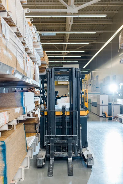 Forklift machine in warehouse near racks with wooden construction materials — Stock Photo